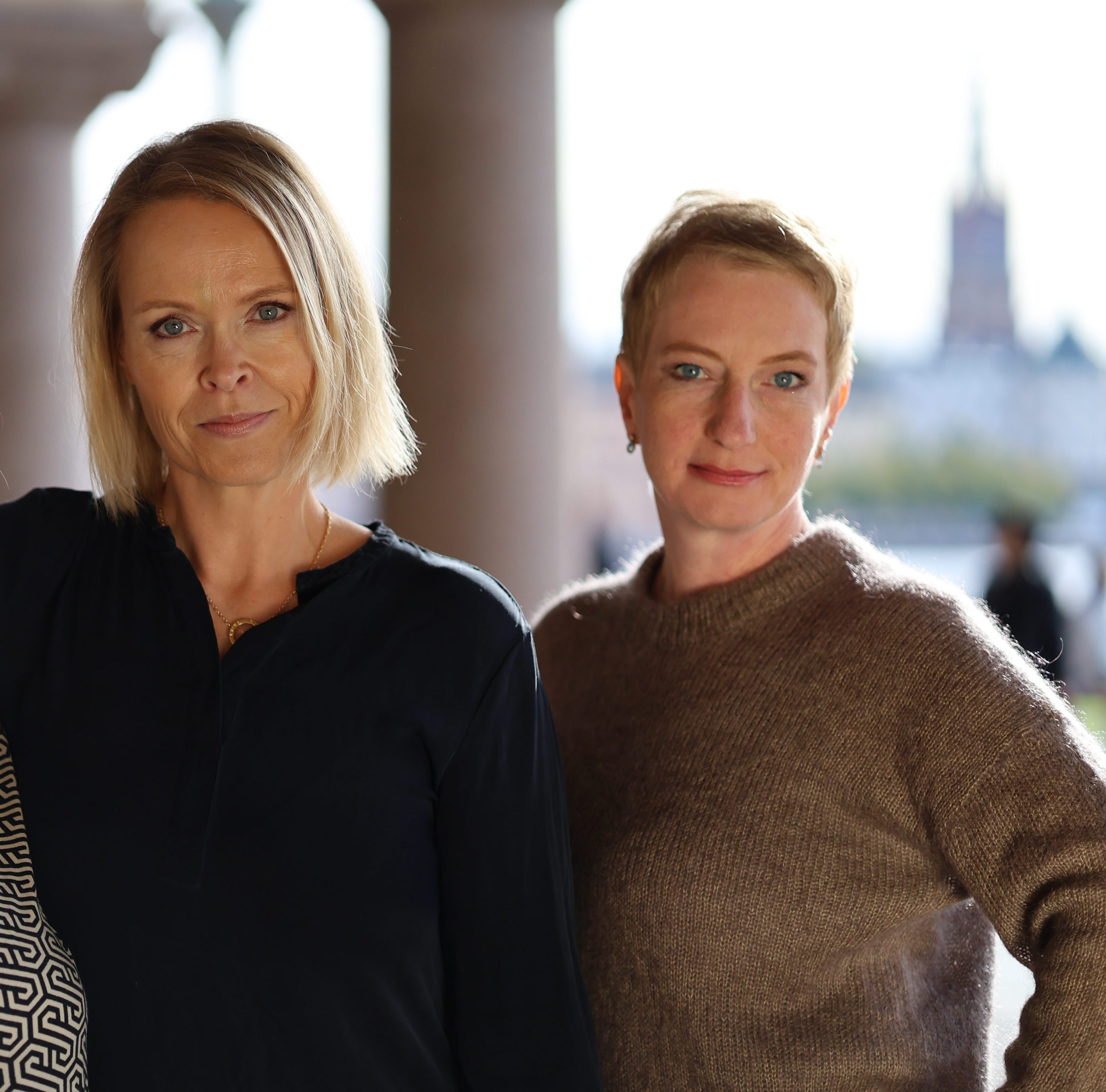 Två kvinnor står tillsammans utomhus i stadsmiljö