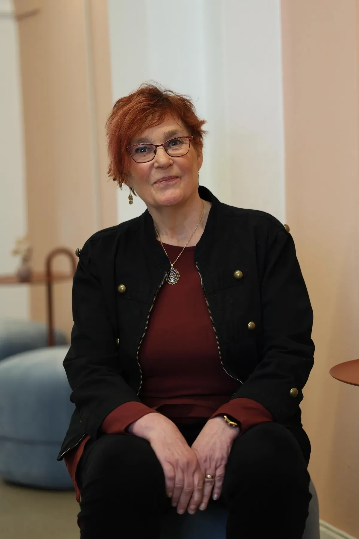 Carina med röd tröja sitter på en stol.